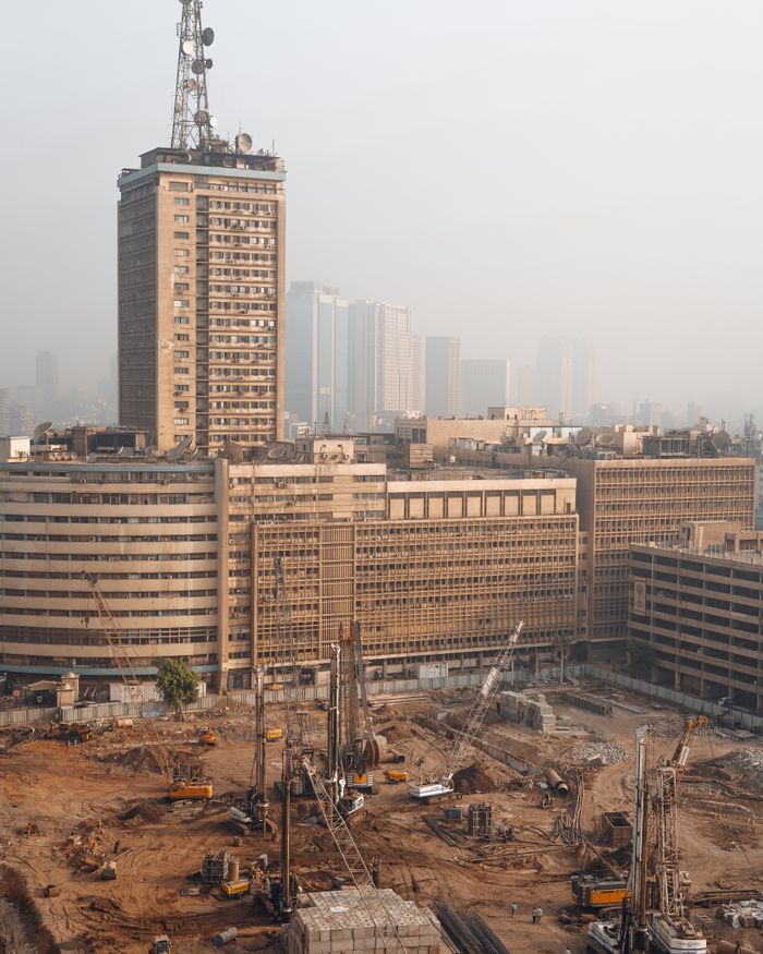 Aerial view of Cairo construction site with hazy skyline and high-rise buildings in Egypt.