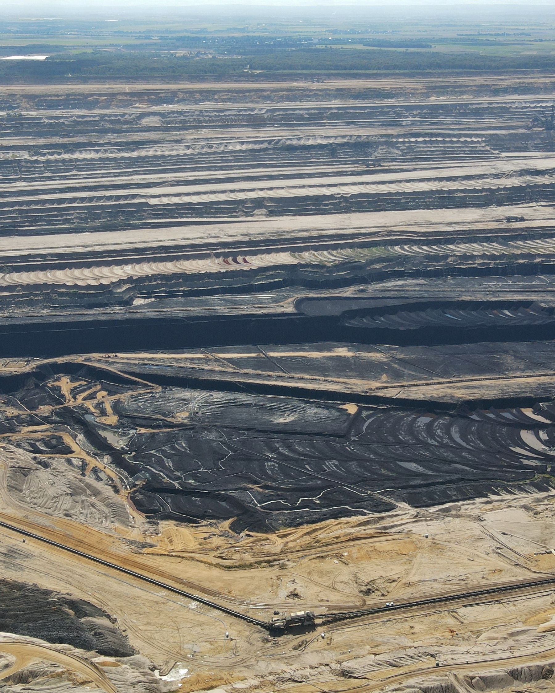 Aerial photograph showcasing a large coal mining site with layered excavations and surrounding landscapes.