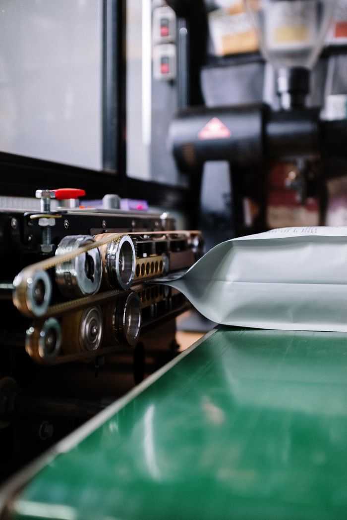 Close-up of industrial sealing machine packaging coffee bag. Perfect for manufacturing themes.